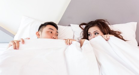 Junges Paar im Bett ein junges paar liegt im bett und denkt über eine Paartherapie in frankfurt nach